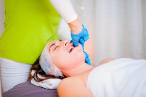 Physiotherapist is making facial massage working on woman's jaw in beauty clinic
